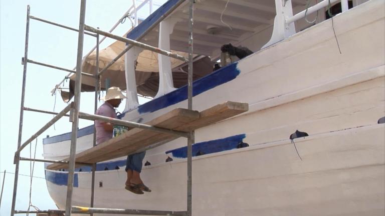 In this image taken from TV Tunisian fisherman Chamseddine Bourrassine paints his boat in Zarzis Tunisia Monday Aug. 5, 2014.  Zarzis is like many other costal towns in Tunisia, it relies heavily on it's fishing industry, which employs many of the local men.The fishermen are netting a catch of a different kind too - migrants who attempt to cross the waters, trying to get in to Europe by sea. Many of these migrants have their sights set on a better life, fleeing conflicts in their home countries. (AP Photo/Associated Press Television)