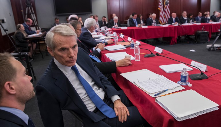 Sen. Rob Portman, R-Ohio, a member of the tax-writing Senate Finance Committee, confers with an aide as tax bill conferees gather to work on the sweeping GOP plan on Capitol Hill. Having reached a final deal on the bill, House Republicans plan to take up tax reform as early as Tuesday, where GOP leaders predict it will pass. (AP Photo/J. Scott Applewhite)