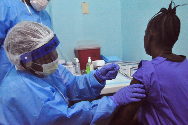 A woman is injected by a health care worker, left, as she takes part in an Ebola virus vaccine trial, in Monrovia, Liberia, Monday, Feb. 2, 2015. (AP Photo/ Abbas Dulleh)