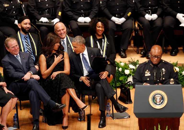 Former President George W. Bush, President Barack Obama and first lady Michelle Obama smile as they react to comments from Dallas Police Chief David Brown during a memorial service at the Morton H. Meyerson Symphony Center in Dallas ,Tuesday, July 12, 2016. Five police officers were killed and several injured during a shooting in downtown Dallas last Thursday night. (AP Photo/Eric Gay)