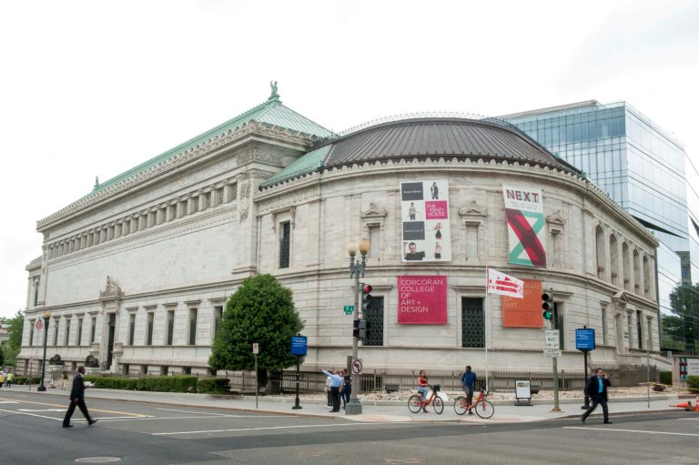 FILE - This May 15, 2014 file photo shows pedestrians passing the Corcoran Gallery of Art in Washington. The District of Columbia has filed court documents in support of allowing the Corcoran Gallery of Art and its college to merge with two larger institutions. D.C. Attorney General Irvin Nathan filed comments this week supporting the museum's merger with George Washington University and the National Gallery of Art. The attorney general is charged with representing the public interest when a court considers major changes to a charity's structure. (AP Photo/Kevin Wolf, File)