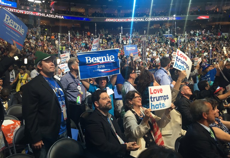 The delegates hoisted signs opposing the Trans-Pacific Partnership trade deal Bernie Sanders opposes as well as signs saying 