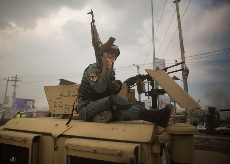 An Afghan policeman rides on top of his armored vehicle as he rushes to the scene as Taliban militants attacked the main Afghan election commission's headquarters on the outskirts of Kabul, Afghanistan, firing on the compound with rocket-propelled grenades and heavy machine guns from a house outside its perimeter wall, Saturday, March 29, 2014. Dozens of employees and other people who had been inside the Independent Election Commission compound took cover in the basement, and no casualties were reported. But two warehouses were hit and set on fire, witnesses said. (AP Photo/Anja Niedringhaus)