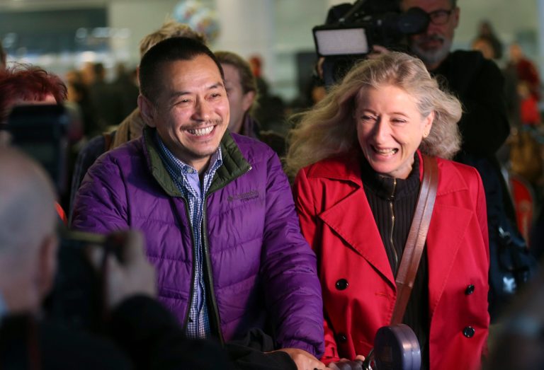 Chinese-born Australian artist Guo Jian, center left, walks with a friend as he arrives at Sydney Airport in Sydney, Australia, Tuesday, June 17, 2014. Guo, detained in Beijing ahead of the politically sensitive 25th anniversary of the deadly military crackdown on protests around Tiananmen Square has been deported to Sydney on Tuesday, Australian Broadcasting Corp. reported.(AP Photo/Rob Griffith)