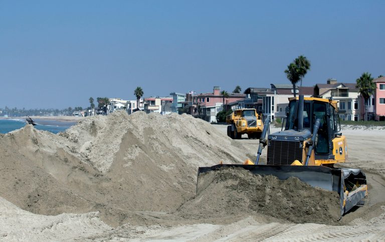 A bulldozer works to pile sand on a temporary berm to protect beach front homes on, Friday, Sept. 5, 2014, in Long Beach, Calif. Southern California is in for another round of high surf generated by what is currently Hurricane Norbert in the Pacific Ocean off Baja California. (AP Photo/Chris Carlson)