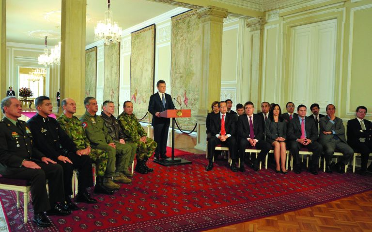 In this photo released by Colombia's Presidential Office, shows President Juan Manuel Santos, center, announcing the signing of a preliminary agreement to launch peace talks with the Revolutionary Armed Forces of Colombia, or FARC, during a nationally televised speech from the presidential palace in Bogota, Tuesday, Sept. 4, 2011. Santos said the talks would begin in early October in Oslo, Norway, and would continue in Havana, Cuba. Sitting at right are cabinet ministers and at left chiefs of the armed forces. (AP Photo/Javier Casella, Colombia's Presidential Office)