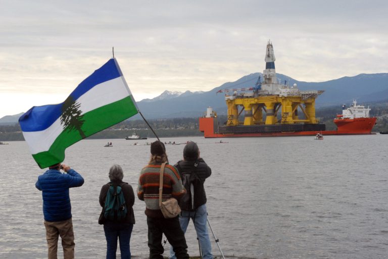 In this April 17, 2015 file photo, protesters watch from Ediz Hook as a flotilla of kayakers paddle out to meet the Arctic offshore oil rig Polar Pioneer piggybacked atop the cargo deck vessel Blue Marlin as it arrived at Port Angeles, Wash. (Keith Thorpe/The Peninsula Daily News via AP, File ) MAGS OUT