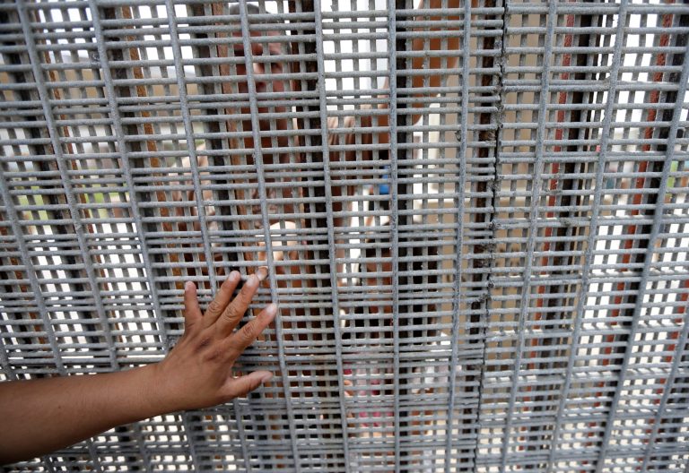 The hand of Marta Lopez, left, touches the finger of her daughter as they stand separated by a fence between Tijuana, Mexico, and San Diego, Calif., during a Sunday mass celebration on July 14. (AP Photo/Gregory Bull)