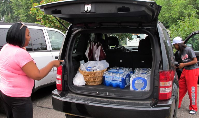 Aundrea Simmons stands next to her minivan with cases of bottled water she bought after Toledo warned residents not to use its water, Saturday, Aug. 2, 2014  in Toledo, Ohio. About 400,000 people in and around Ohio's fourth-largest city were warned not to drink or use its water after tests revealed the presence of a toxin possibly from algae on Lake Erie. (AP Photo John Seewer)