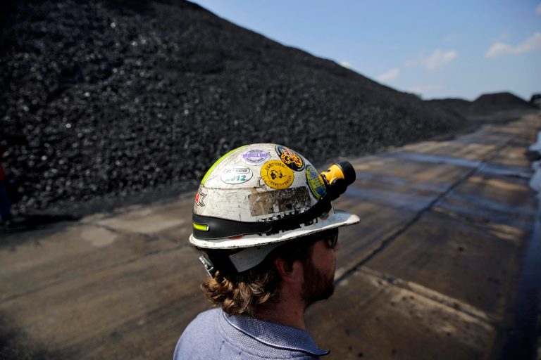 In this May 22, 2014, file photo, Wesley Simon-Parsons, civil and environmental supervisor at Dominion Terminal Associates, stands near piles of coal at the company's coal terminal in Newport News, Va. (AP Photo/Patrick Semansky, File)