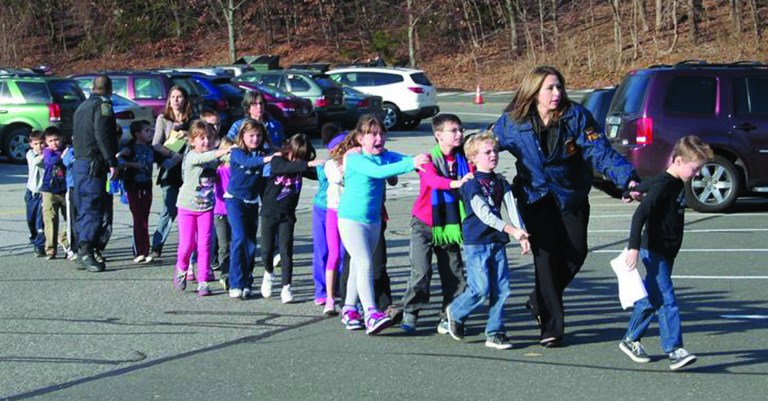 In this photo provided by the Newtown Bee, Connecticut State Police lead children from the Sandy Hook Elementary School in Newtown, Conn., following a reported shooting there Friday, Dec. 14, 2012. (AP Photo/Newtown Bee, Shannon Hicks) MANDATORY CREDIT