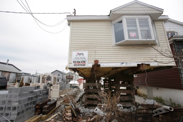FILE- In this April 11, 2013, file photo, a home in the process of being raised is seen in the Broad Channel section of Queens, New York. About 24,000 families have signed up for New York City's Build-It-Back program, which will help pay for repairs, elevate their homes and reimburse them for repairs that have already completed on the damage left behind by Superstorm Sandy.  On Thursday, April 17, 2014, New York City Mayor Bill de Blasio announced changes to the program. Criticizing the program as 