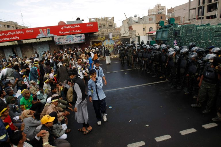 Hawthi Shiite protesters sit on the ground to prevent riot police vehicles advancing during a protest in a main road leading to the airport in Sanaa, Yemen, Sunday, Sept. 7, 2014. Yemeni security forces moved to break up a sit-in held by Shiite rebels blocking the capital's airport road on Sunday, using water cannons, bulldozers and tear gas, security officials and witnesses said. (AP Photo/Hani Mohammed)