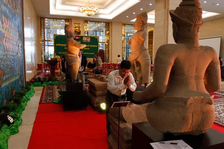 A Cambodian man prays at the three pieces of the 10th century Cambodian sandstone statues displayed after returning from the United States during a handover ceremony at the Council of Ministers in Phnom Penh, Cambodia, Tuesday, June 3, 2014. Cambodia has welcomed back three statues that had been in Western art collections after having been looted from a 1,000-year-old temple during war. (AP Photo/Heng Sinith)