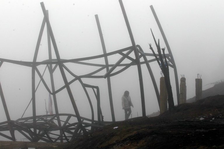 A woman walks through the remains of a house destroyed by a wildfire, in Valparaiso, Tuesday April 15, 2014. A raging fire leaped from hilltop to hilltop in this port city, killing more than a dozen people and destroying thousands of homes. (AP Photo/Luis Hidalgo).