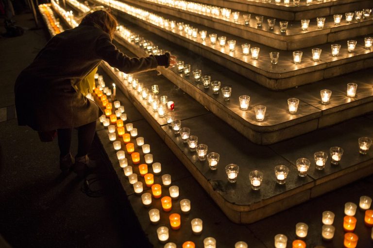 A woman lights a candle as about 15,000 people gather for a moment of silence in Lyon, central France, to pay their respects to the victims of the French newspaper Charlie Hebdo's attack, Wednesday, Jan. 7, 2015. (AP Photo/Laurent Cipriani)