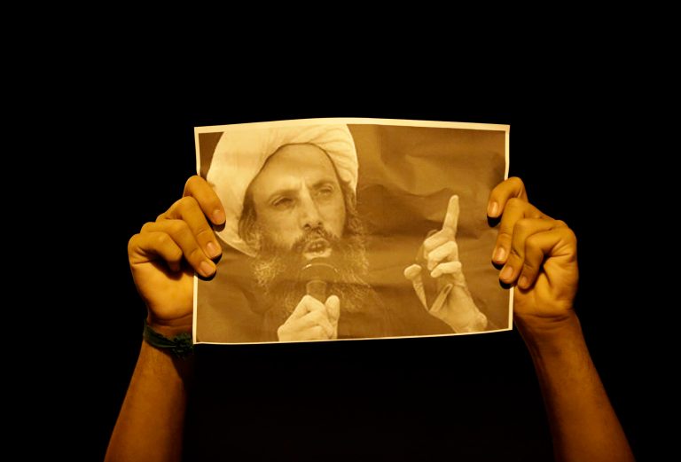 A Bahraini anti-government protester holds up a picture of jailed Saudi Sheik Nimr al-Nimr during clashes with riot police in Sanabis, Bahrain, a suburb of the capital Manama, Wednesday night, Oct. 15, 2014. The well-known Shiite cleric was sentenced to death Wednesday by a court in Saudi Arabia, sparking fears of renewed unrest from his supporters in the kingdom and neighboring Bahrain. (AP Photo/Hasan Jamali)