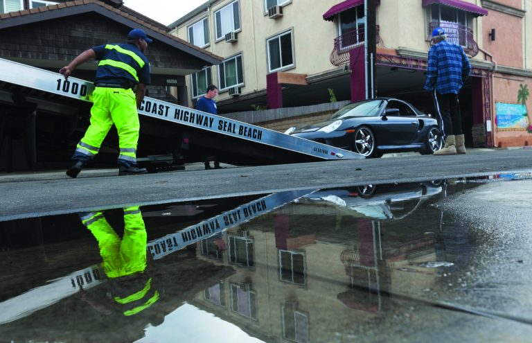 A Porsche Sports car is towed away after flood waters damaged its electric systems near the overflowed streets onto Pacific Coast Highway in the Sunset Beach area of Huntington Beach, Calif., Thursday, Dec. 13, 2012. Astronomical high tides have caused minor street flooding in some low-lying areas along the Southern California coast. (AP Photo/Damian Dovarganes)