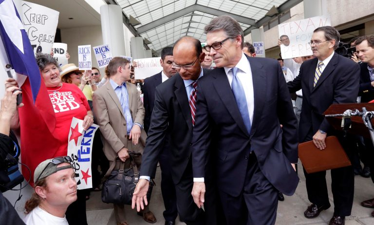 Texas Gov. Rick Perry, front right, is escorted away from the Blackwell Thurman Criminal Justice Center, in Austin, Texas on Aug. 19, 2014. (AP Photo/Eric Gay, File)