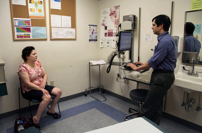 Patient Amanda Thornton, left, of Aloha, Ore., speaks with primary care doctor John Guerreiro at a clinic run by the Virginia Garcia Memorial Health Center in Beaverton, Ore. (AP Photo/Gosia Wozniacka)