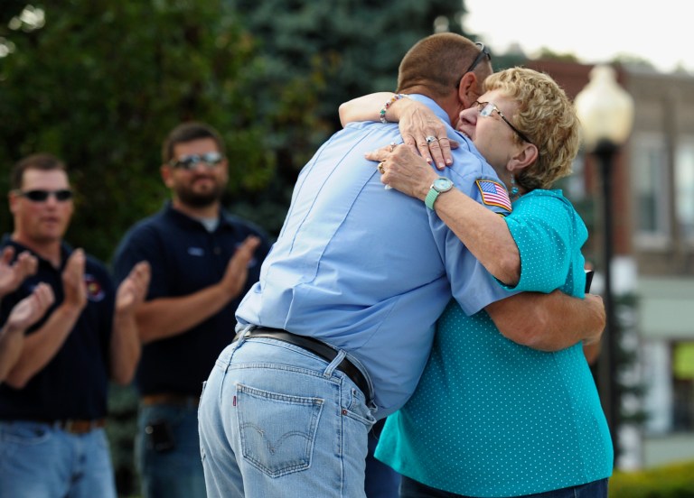 In this Tuesday, July 15, 2014 photo, Prophetstown, Ill., resident Dolores Francis hugs Erie firefighter Joe Froeliger during a presentation at a community cookout in Prophetstown marking the first anniversary of a devastating fire that damaged eight buidlings in the city's downtown area. The city presented plaques to Froeliger, and fellow firefighters who were credited for getting Francis out of one of the burning buildings that night.  (AP Photo/The Dispatch, Todd Welvaert)  QUAD CITY TIMES OUT