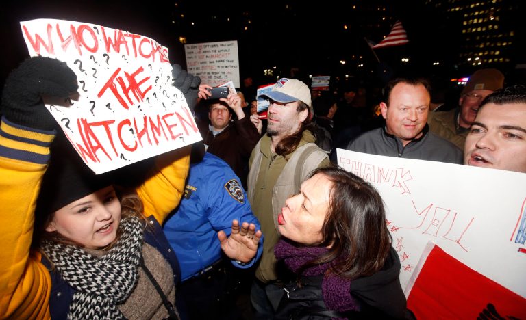 An anti-police demonstrator, left, and a pro-police demonstrator, center, confront one another during a pro-police rally outside City Hall held in response to a string of recent anti-police protests, Friday, Dec. 19, 2014, in New York. (AP Photo/Jason DeCrow)