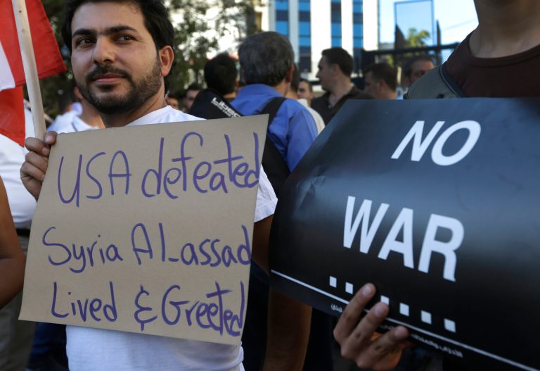   Lebanese pro-Syrian regime supporters hold placards as they gather during a demonstration against a possible military strike in Syria, near the U.S. Embassy in Aukar, east of Beirut, Lebanon, Friday, Sept. 6, 2013. The prospect of a U.S.-led strike against Syria has raised concerns of potential retaliation from the Assad regime or its allies. The State Department ordered nonessential U.S. diplomats to leave Lebanon over security concerns and urged private American citizens to depart as well. (AP Photo/Hussein Malla)  