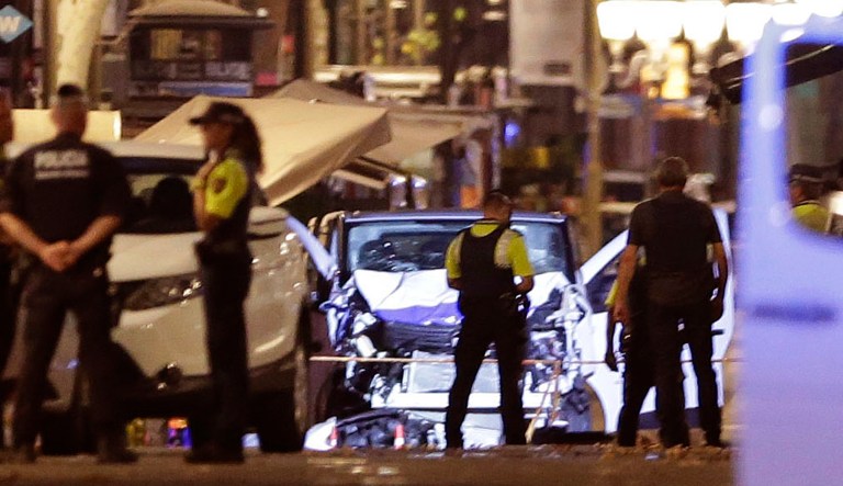 Police officers stand next to the van involved on an attack in Las Ramblas in Barcelona, Spain, Thursday, Aug. 17, 2017. A white van jumped up onto a sidewalk and sped down a pedestrian zone Thursday in Barcelona's historic Las Ramblas district, swerving from side to side as it plowed into tourists and residents. Police said 13 people were killed and more than 50 wounded in what they called a terror attack. (AP Photo/Manu Fernandez)