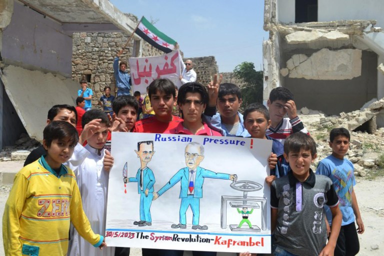 In this citizen journalism image provided by Edlib News Network, ENN, which has been authenticated based on its contents and other AP reporting, anti-Syrian regime protesters hold a poster depicting Syrian President Bashar Assad, left, and Russian Foreign Minister Sergei Lavrov, right, during a demonstration, at Kafr Nabil town, in Idlib province, northern Syria, Friday May 10, 2013. Arabic banner on the background reads, 