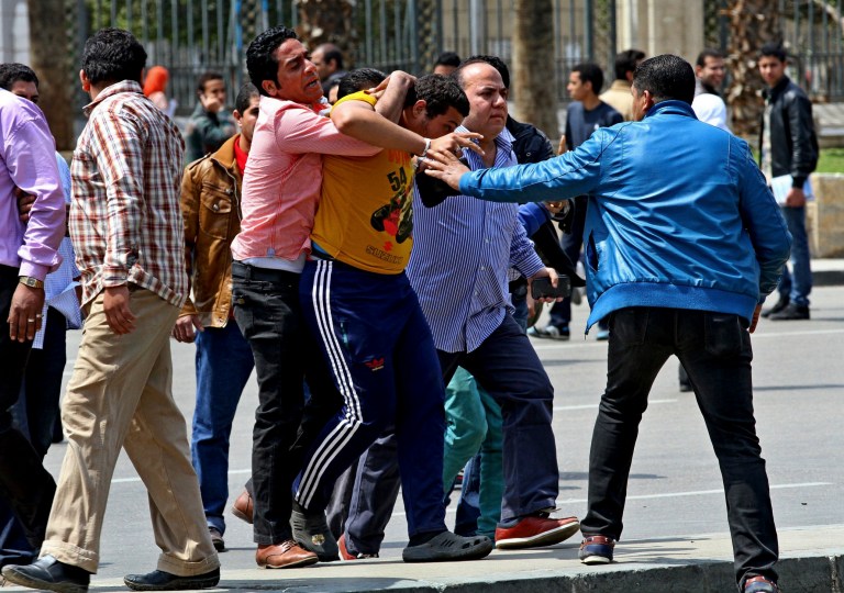 Plainclothes Egyptian security forces detain people at the scene of deadly explosions that hit the area outside the main campus of Cairo University, in Giza, Egypt, Wednesday, April 2, 2014. Three bombs exploded Wednesday, hitting riot police deployed against near daily protests by Islamist students amid a fierce crackdown by security forces against protesters and supporters of ousted Islamist President Mohammed Morsi. (AP Photo/Hussein Tallal)