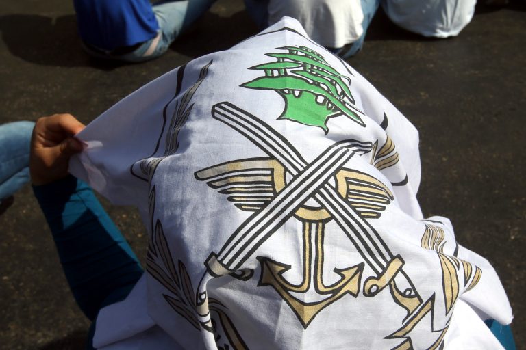 A relative of a missing Lebanese soldier who was kidnapped by Islamic State militants covers her head with the Lebanese army flag as she sits on the ground street during a demonstration to demand action to secure the captives' release, in front the Lebanese government building, in downtown Beirut, Lebanon, on Thursday, Sept. 4, 2014. Lebanon's government is forming a crisis committee to handle the case of some two dozen members of the security forces held captive by Syrian militants amid escalating criticism over its response to the hostage affair. (AP Photo/Hussein Malla)