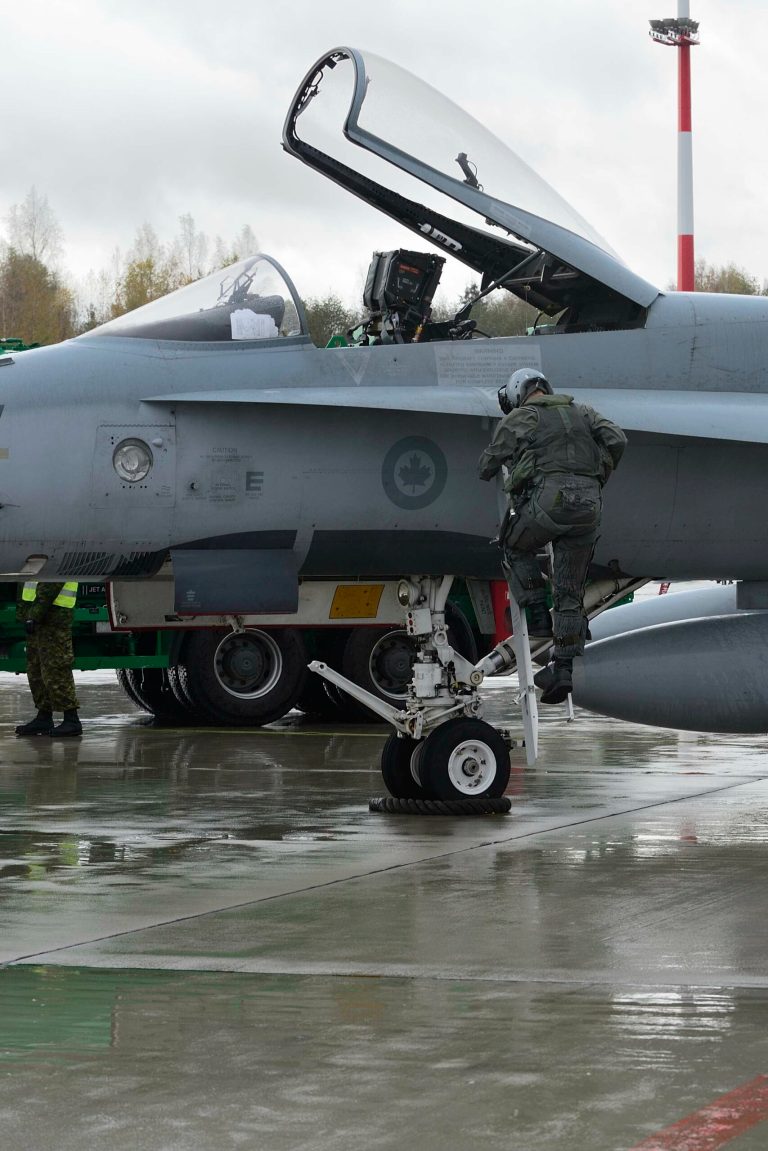 A pilot  climbs from a Canadian Air Force F-18 Hornet at Siauliai Air Base in Lithuania Monday Oct. 20, 2014 . Two Canadian F-18 Hornet jets were scrambled from the Siauliai Air Base in Lithuania on Monday to intercept a Russian Ilyushin-20 surveillance aircraft, which they shadowed for some 15 minutes, NATO said. (AP Photo/Canadian Air Force, Cpl Gabrielle DesRochers)