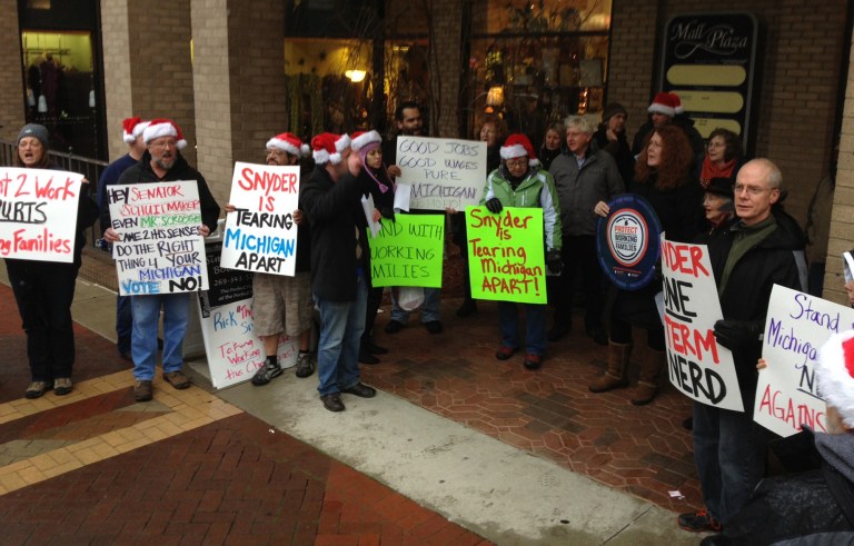  Dozens of union backers protest against the right-to-work bills outside Sen. Tonya Schuitmaker's Kalamazoo, Mich., office Sunday, Dec. 9, 2012. People sang Christmas-themed protest songs and carried picket signs outside the office of the Republican state senator, who received a bag of coal from union-rights demonstrators protesting her vote to make Michigan a right-to-work state. (AP Photo/The Kalamazoo Gazette, Aaron Mueller) ALL LOCAL TV OUT; LOCAL TV INTERNET OUT  