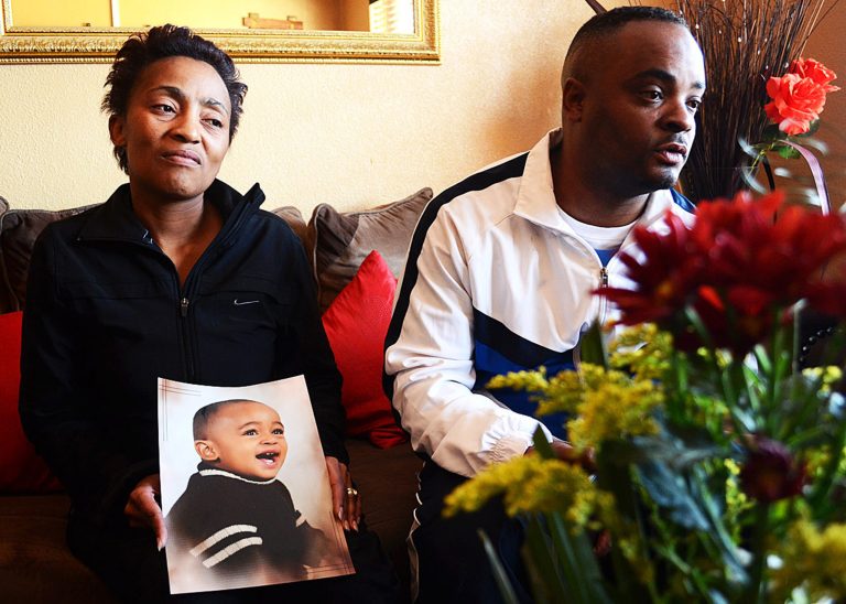 In this photo taken Sunday July 20, 2014 Chantel, left, and Elwin Morris, right pose with a photo of their son, Taegrin, at their home in Boksburg, east of Johannesburg. South African media say the boy was with his sister and parents during a carjacking Saturday night. His mother told The Star newspaper that her son's foot got stuck as she tried to pull him from the car, but the carjackers sped off. The boy was later found dead in the abandoned vehicle. (AP Photo/The Star, Timothy Bernard)  SOUTH AFRICA OUT
