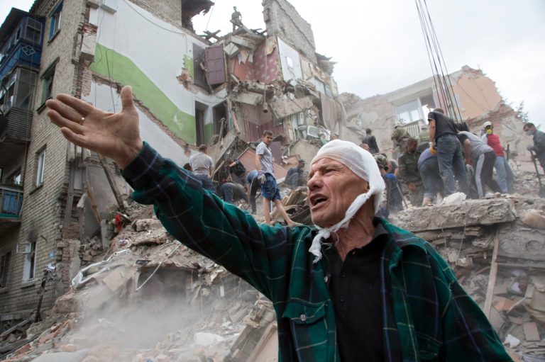 Igor Chernetsov whose wife was killed in collapsed building during airstrike gestures near his house in Snizhne, 100 kms east from the city of Donetsk, eastern Ukraine Tuesday, July 15, 2014. An airstrike demolished an apartment block in eastern Ukraine on Tuesday, killing at least nine civilians, rescue workers said. The attack adds to the steadily growing number of civilians killed over four months in a dogged pro-Russian insurgency. Government officials denied the Tuesday strike was carried out by Ukraine's air force. (AP Photo/Dmitry Lovetsky)