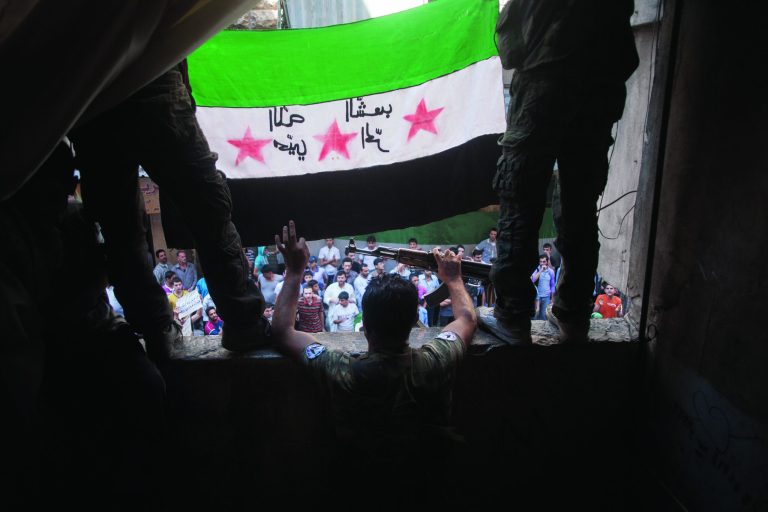 In this Friday, Sept. 21, 2012 photo, Free Syrian Army rebels hold a revolutionary flag on it during a demonstration in the Bustan al-Qasr neighborhood of Aleppo, Syria. The Britain-based Syrian Observatory for Human Rights said Friday that nearly 30,000 Syrians have been killed during the 18-month uprising against the Assad regime. Arabic on flag is reversed, but reads, 