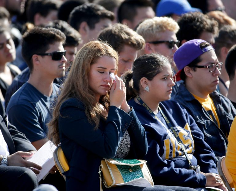 A woman wipes a tear at a memorial service for the victims and families of Friday's rampage at Harder Stadium on the campus of University of California, Santa Barbara on Tuesday in the Isla Vista area near Goleta, Calif. (AP Photo/Chris Carlson)