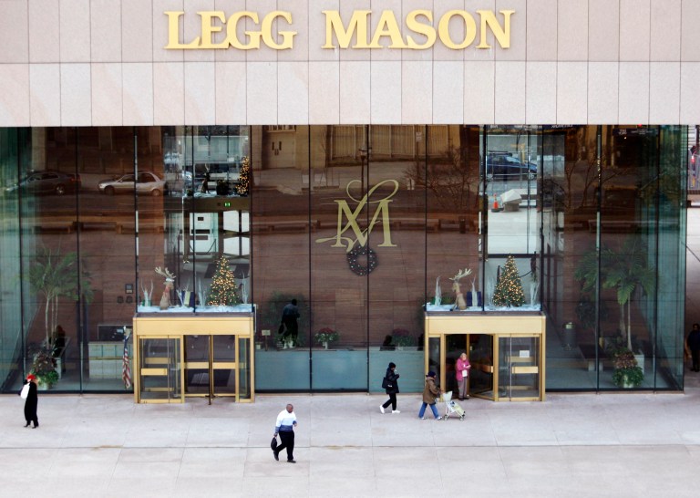 FILE - In this Dec. 5, 2008 file photo, people exit the Legg Mason Building in Baltimore. Legg Mason Inc.  A subsidiary of investment firm Legg Mason Inc. has agreed to pay about $21 million to settle U.S. government claims that it concealed losses to investors and engaged in prohibited transactions that favored some clients over others. (AP Photo/Rob Carr, File)