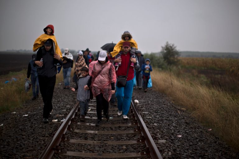 Syrian refugees walk on a railway track toward a makeshift camp for asylum seekers in Roszke, southern Hungary, Thursday, Sept. 10, 2015. (AP Photo/Muhammed Muheisen)