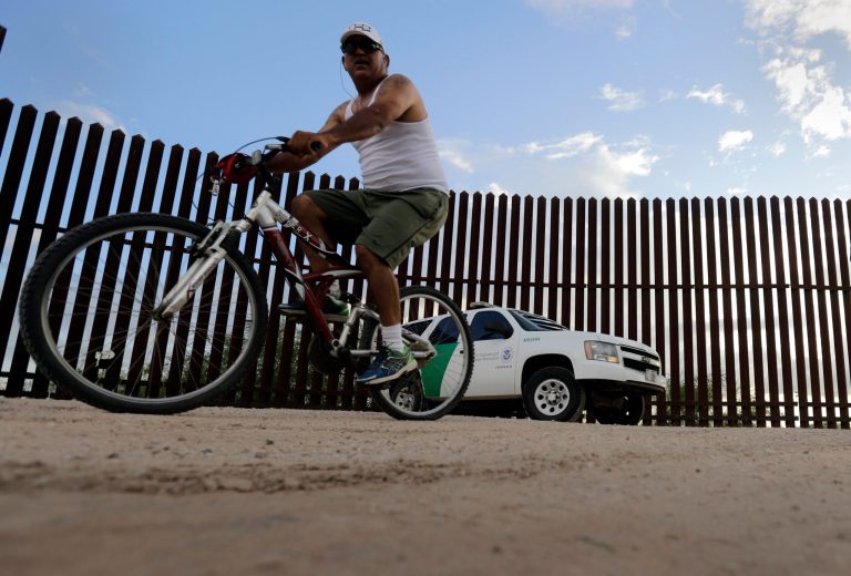 A cyclist passes a U.S. Customs and Border Patrol agent along the border fence in Hidalgo, Texas. (AP Photo/Eric Gay)