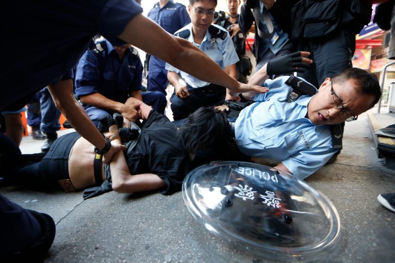 A pro-democracy protester is arrested by riot polices after police moved in the occupied area by the protesters in the Mong Kok district of Hong Kong, early Friday, Oct. 17, 2014. Riot police moved in on a Hong Kong pro-democracy protest zone in a dawn raid on Friday, taking down barricades, tents and canopies that have blocked key streets for more than two weeks. (AP Photo/Kin Cheung)