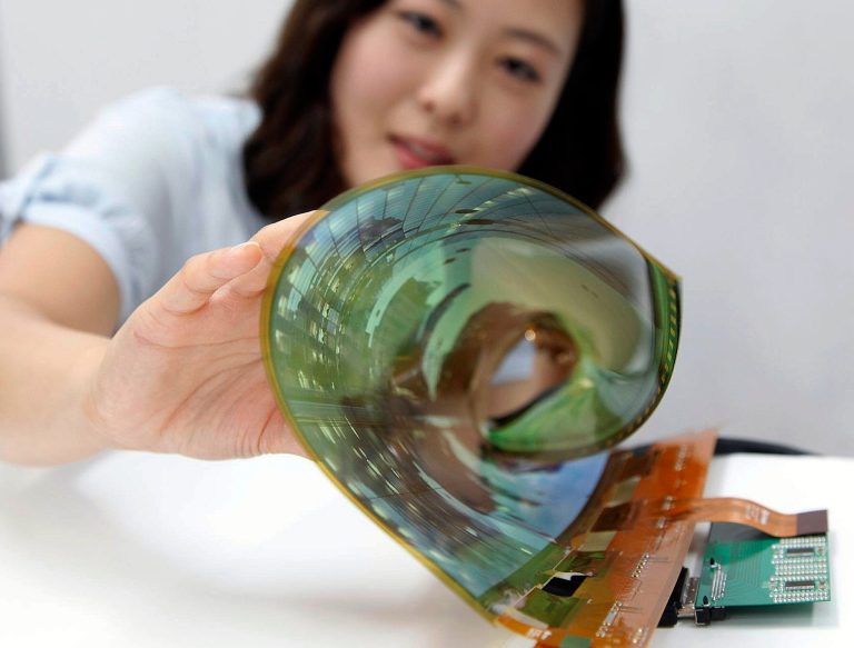 In this July 9, 2014 photo released by LG Display Co., an employee at the company demonstrates an 18-inch flexible display, in Seoul, South Korea. The South Korean display panel maker said Friday, July 11, 2014 it has developed the 18-inch flexible display that can be rolled into the shape of a thin cylinder, a step closer to making a large-size display for flexible TVs. (AP Photo/LG Display Co.)