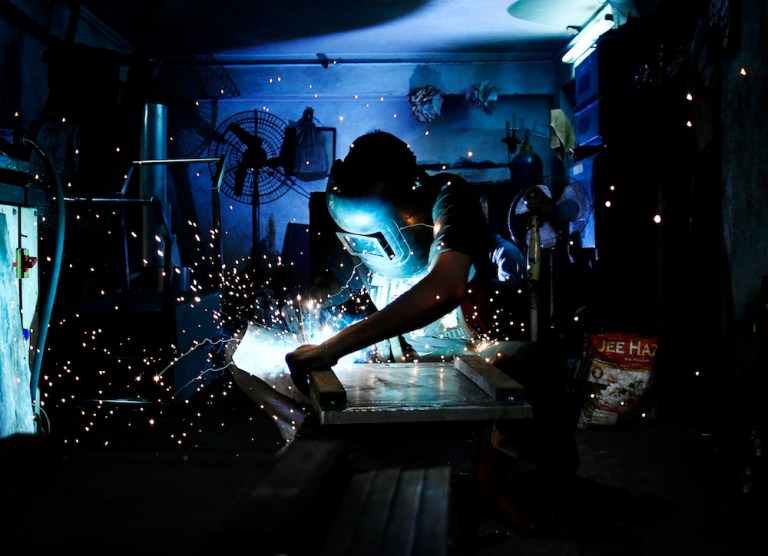 A worker wearing a protective mask cuts a sheet of steel at a factory. President Trump's tariffs on steel and aluminum imports may provoke a broader trade war, corporate executives have warned, and raise questions about existing U.S. alliances. (Anindito Mukherjee/Bloomberg)
