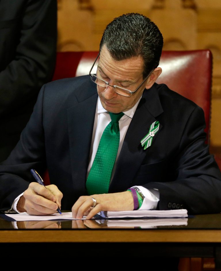 Connecticut Gov. Dannel P. Malloy signs legislation at the Capitol in Hartford, Conn., Thursday, April 4, 2013, which includes new restrictions on weapons and large capacity ammunition magazines, a response to last year's deadly school shooting in Newtown. The legislation adds more than 100 firearms to the state's assault weapons ban, sets eligibility rules for buying ammunition, and creates what officials have called the nation's first dangerous weapon offender registry. Some parts of the bill would take effect immediately after Malloy's signature, including background checks for all firearms sales. (AP Photo/Steven Senne)