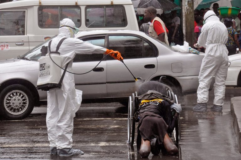 Health workers spray the body of a amputee suspected of dying from the Ebola virus with disinfectant, in a busy street in Monrovia, Liberia, Tuesday, Sept. 2, 2014.  Food in countries hit by Ebola is getting more expensive and will become scarcer because many farmers won't be able to access fields, a U.N. food agency warned Tuesday. An Ebola outbreak in West Africa has killed more than 1,500 people, and authorities have cordoned off entire towns in an effort to halt the virus' spread.  (AP Photo/Abbas Dulleh)
