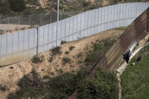 A man walks along the Mexico side of the old border fence as the newer fence sits in the distance Tuesday, Jan. 29, 2013, in Tijuana, Mexico. The President on Tuesday praised bipartisan efforts to overhaul the nation's immigration laws, welcoming 