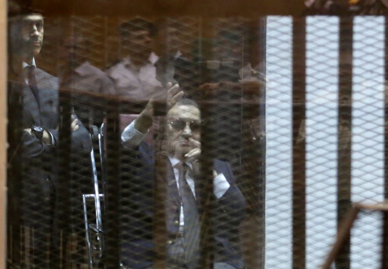 Former Egyptian President Hosni Mubarak, seated, waves to his supporters as he attends with his two sons Gamal Mubarak, left, and Alaa Mubarak, the verdict in the corruption case dubbed by the Egyptian media as the 