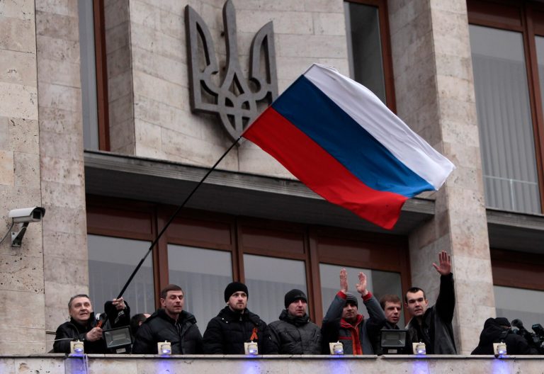 Demonstrators holding a Russian flag stand on the balcony of a regional administrative building after storming it, in Donetsk, Ukraine, on Wednesday. (AP Photo/Sergei Chuzavkov)