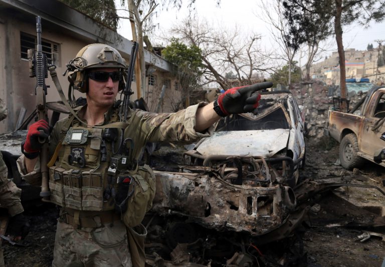 A U.S. soldier stands at the site where a suicide bombers have attacked a police compound in Surobi district of Kabul, Afghanistan, Friday, Feb. 21, 2014. (AP Photo/Rahmat Gul)