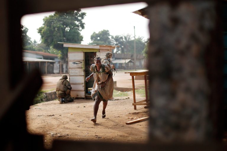 A woman runs for cover as heavy gunfire erupts in the Miskin district of Bangui, Central African Republic, Monday Feb. 3, 2014. In what a French soldier on the scene describes as the heaviest exchange of fire he'd seen since early December 2013, Muslim militias engaged Burundi troops who returned fire. A third source of firing remained unidentified. Fighting between Muslim Seleka militias and Christian anti-Balaka factions continues as French and African Union forces struggle to contain the bloodshed. (AP Photo/Jerome Delay)